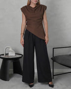 una mujer con blusa asimetrica de hombreras marron y pantalon negro