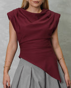 una mujer con blusa asimetrica de hombreras vinotinto
