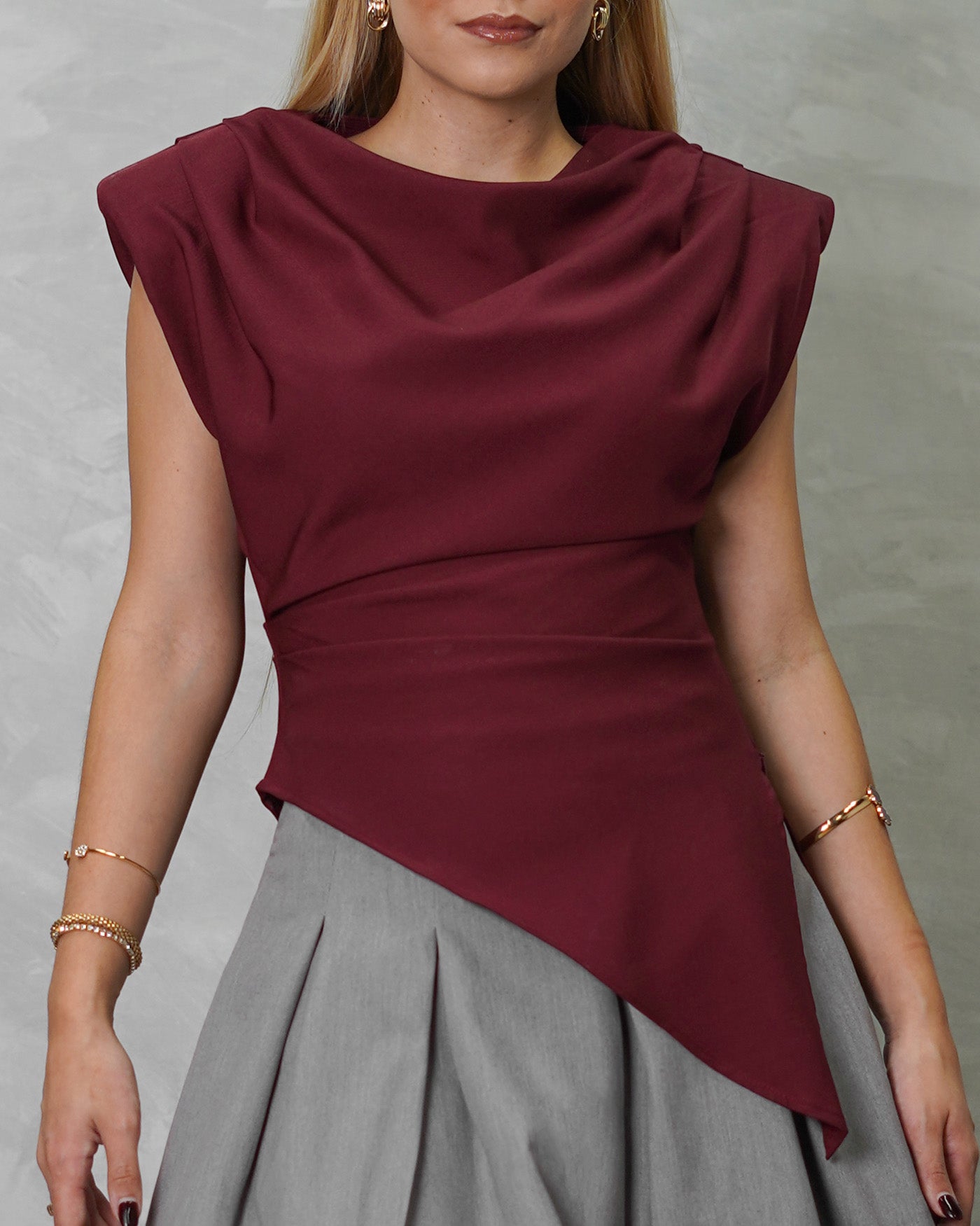 una mujer con blusa asimetrica de hombreras vinotinto