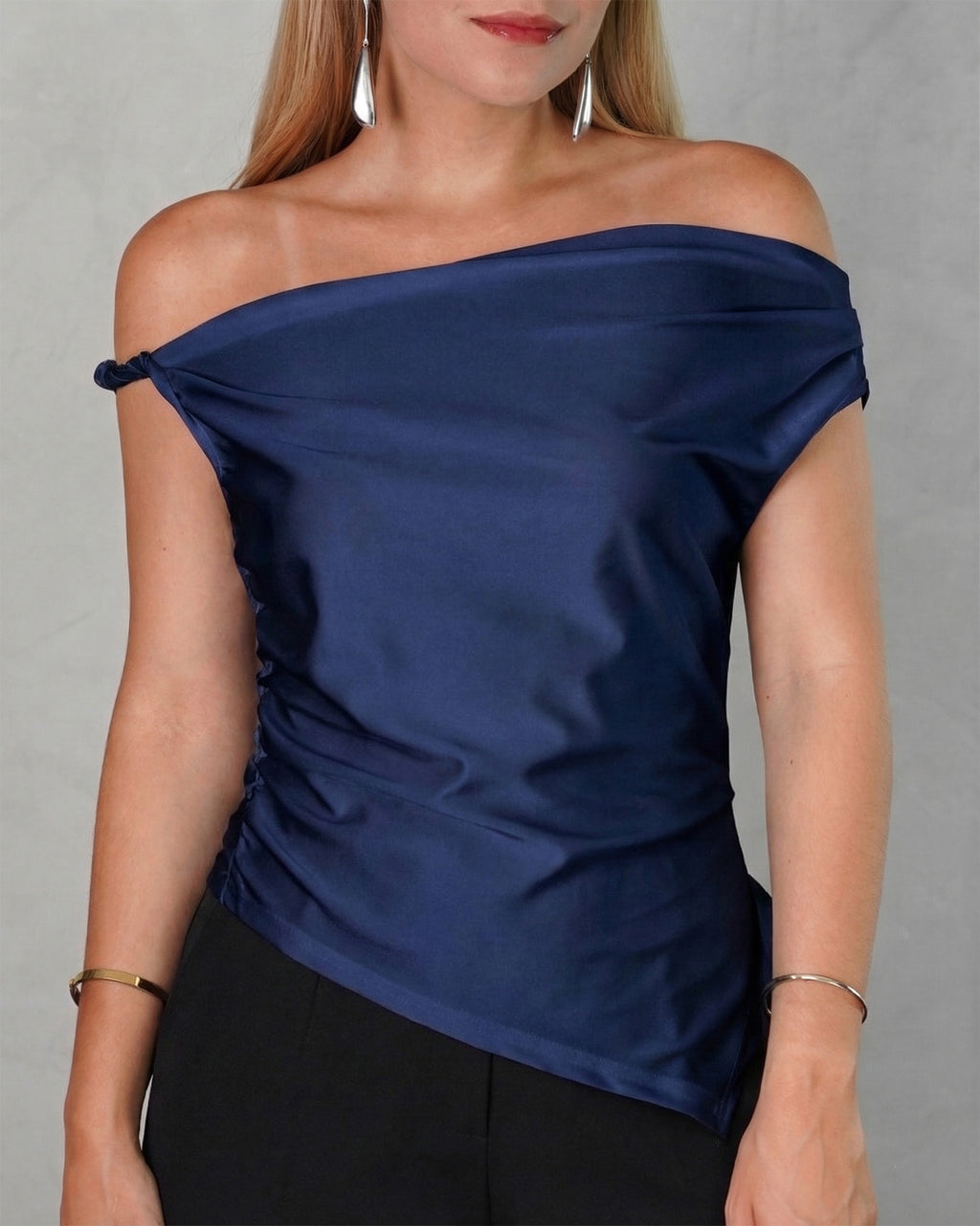 mujer con una blusa asimetrica de hombro amarrado azul marino