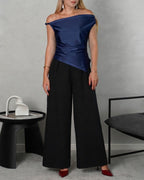 mujer con una blusa asimetrica de hombro amarrado azul marino y pantalon negro