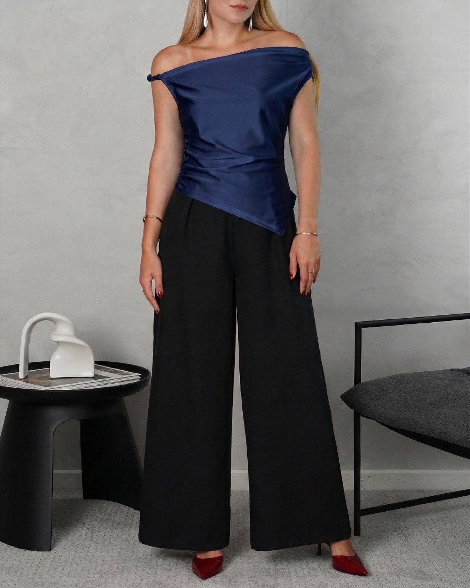 mujer con una blusa asimetrica de hombro amarrado azul marino y pantalon negro