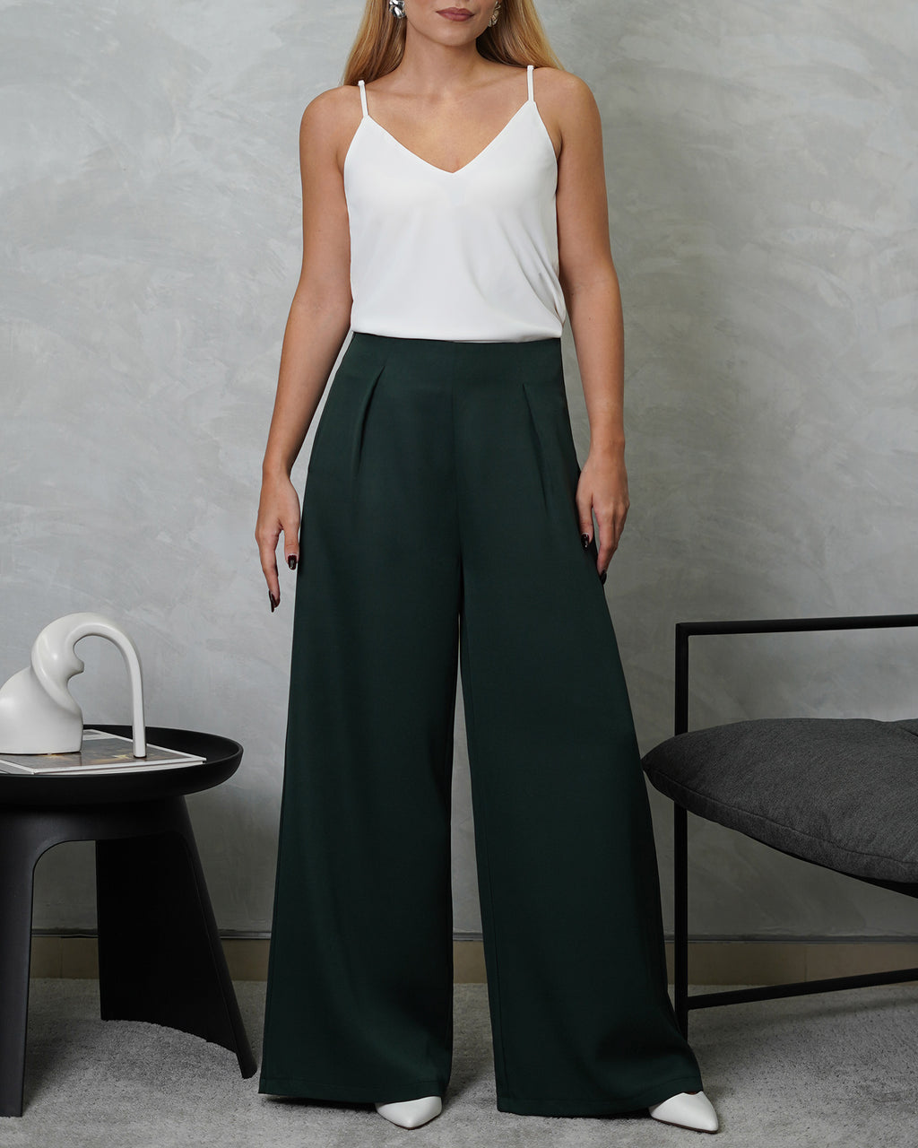 una mujer con una blusa básica de tiras cuello V blanca y pantalon verde oscuro