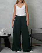 una mujer con una blusa básica de tiras cuello V blanca y pantalon verde oscuro