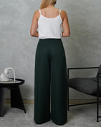 una mujer de espalda con una blusa básica de tiras cuello V blanca y pantalon verde oscuro