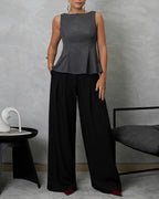 mujer de cuerpo completo usando blusa campanada de espalda escotada gris y pantalon negro