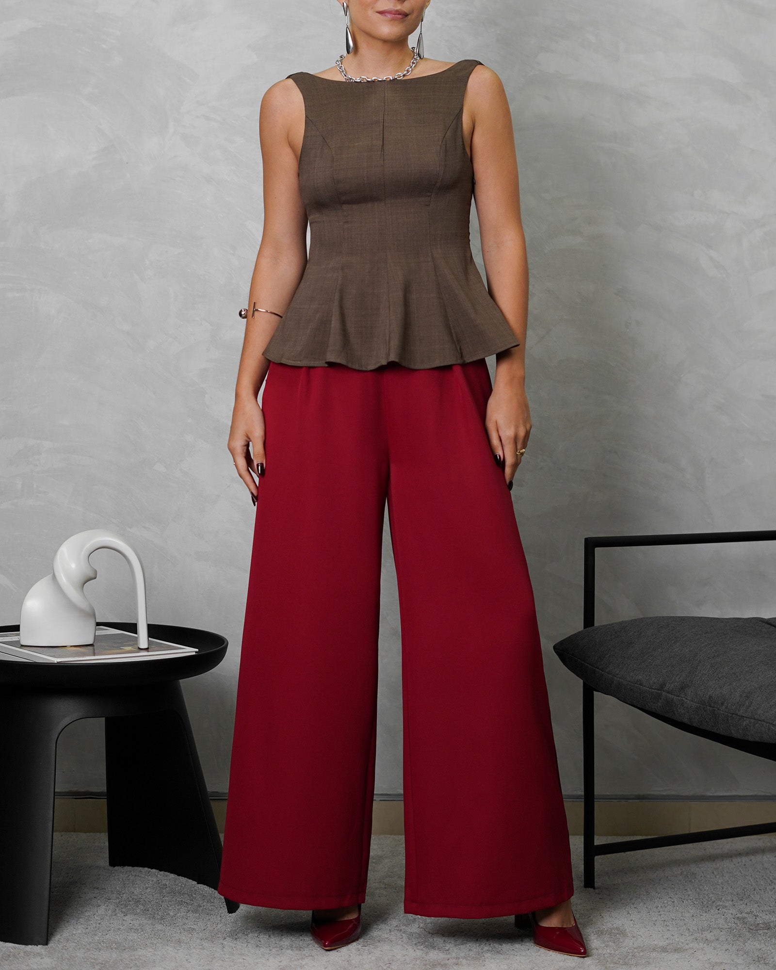 mujer de cuerpo completo usando blusa campanada de espalda escotada marron y pantalon vinotinto