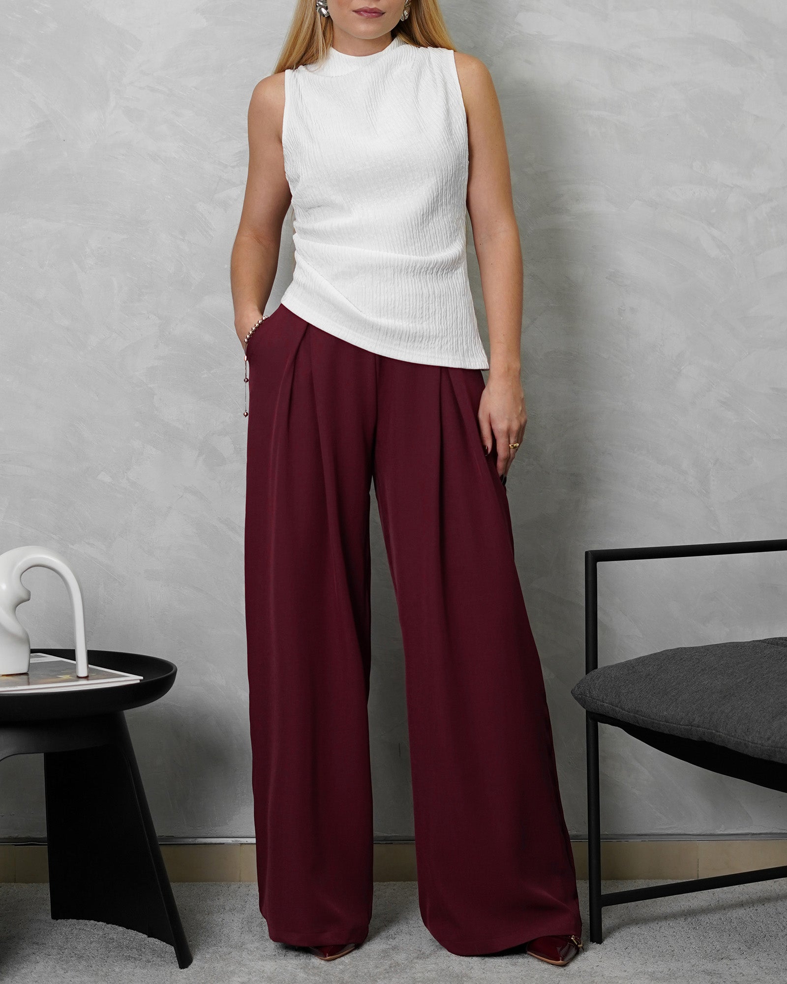 una mujer con una busa corte alto asimetrica con textura blanco y pantalon vinotinto