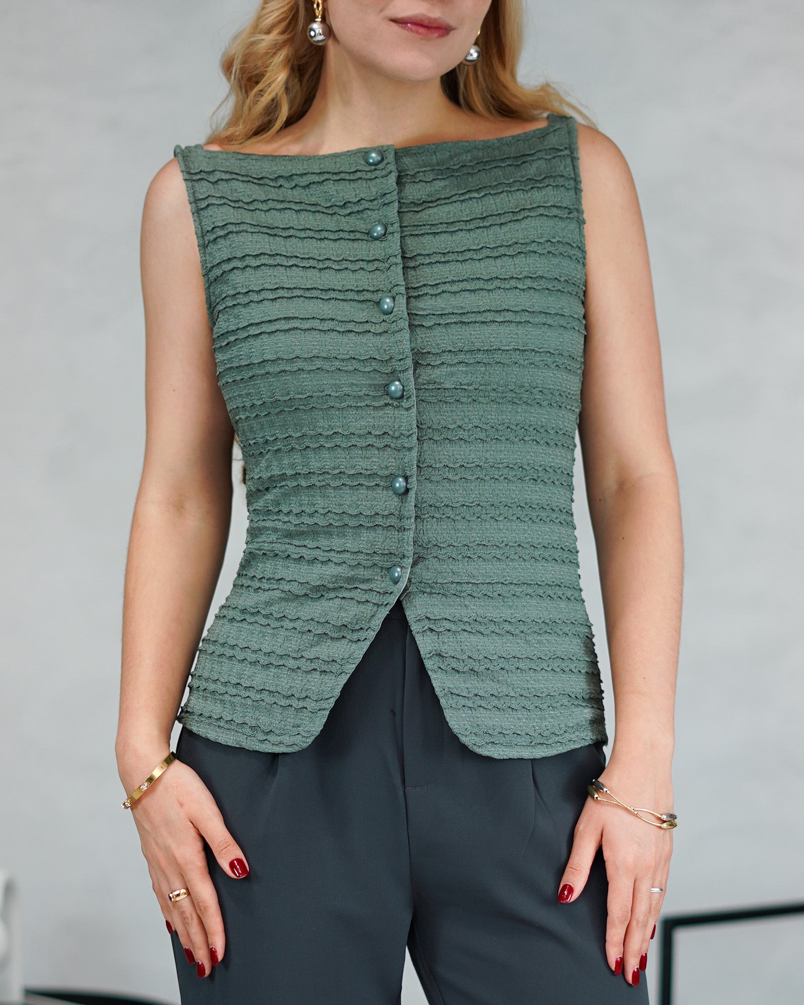 una mujer con una blusa corte recto con textura y botones de perla verde