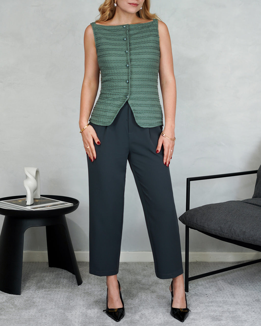 una mujer con una blusa corte recto con textura y botones de perla verde y pantalon gris oscuro