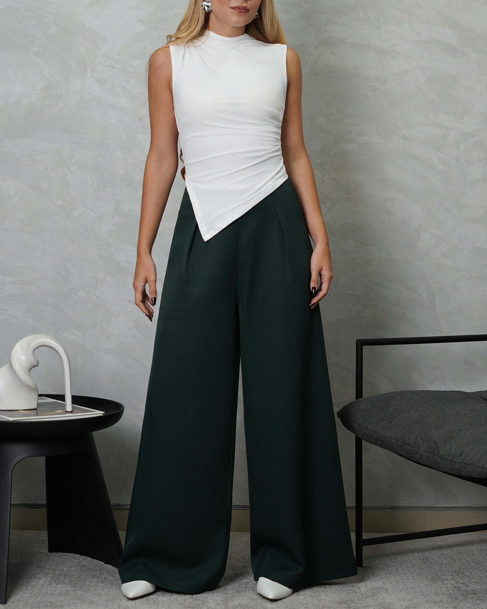 una mujer con blusa de corte bajo en v blanca y pantalon verde oscuro 