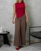 una mujer con blusa de corte bajo en v vinotinto y pantalon marron