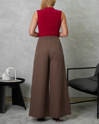 una mujer de espalda con blusa de corte bajo en v vinotinto y pantalon marron