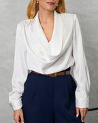 una mujer con blusa de seda manga larga cuello bobo blanco 