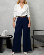 una mujer con blusa de seda manga larga arremangada cuello bobo blanco y pantalon azul marino