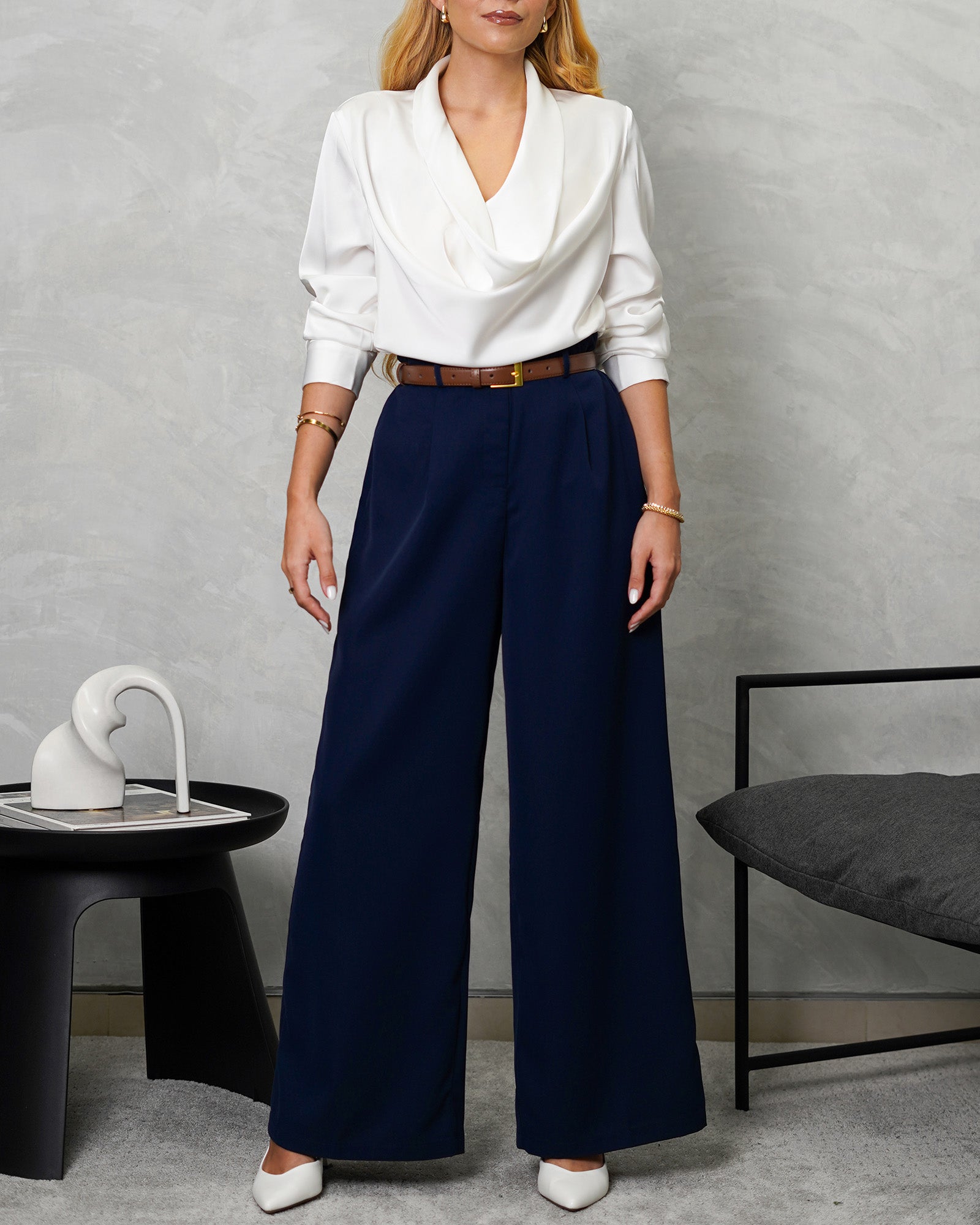 una mujer con blusa de seda manga larga arremangada cuello bobo blanco y pantalon azul marino