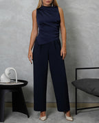 Una mujer con blusa de seda sin mangas cuello asimetrico azul marino y pantalon azul marino