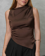 Una mujer con blusa de seda sin mangas cuello asimetrico marron