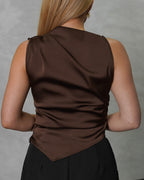 Una mujer de espalda con blusa de seda sin mangas cuello asimetrico marron