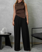 Una mujer con blusa de seda sin mangas cuello asimetrico marron y pantalon negro