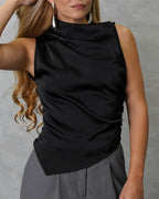 Una mujer con blusa de seda sin mangas cuello asimetrico negro