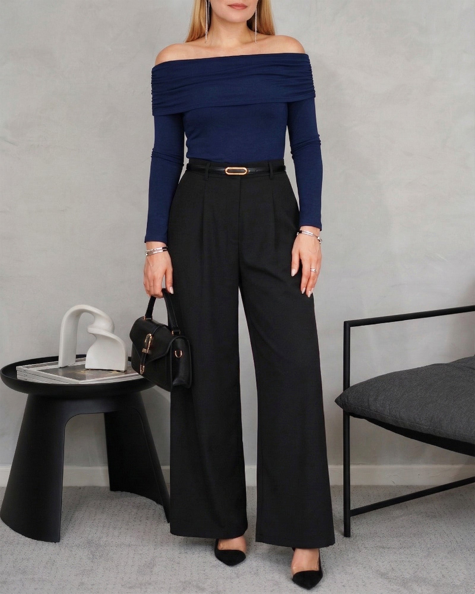 mujer con Blusa manga larga strapless azul marino y pantalon negro con correa dorada