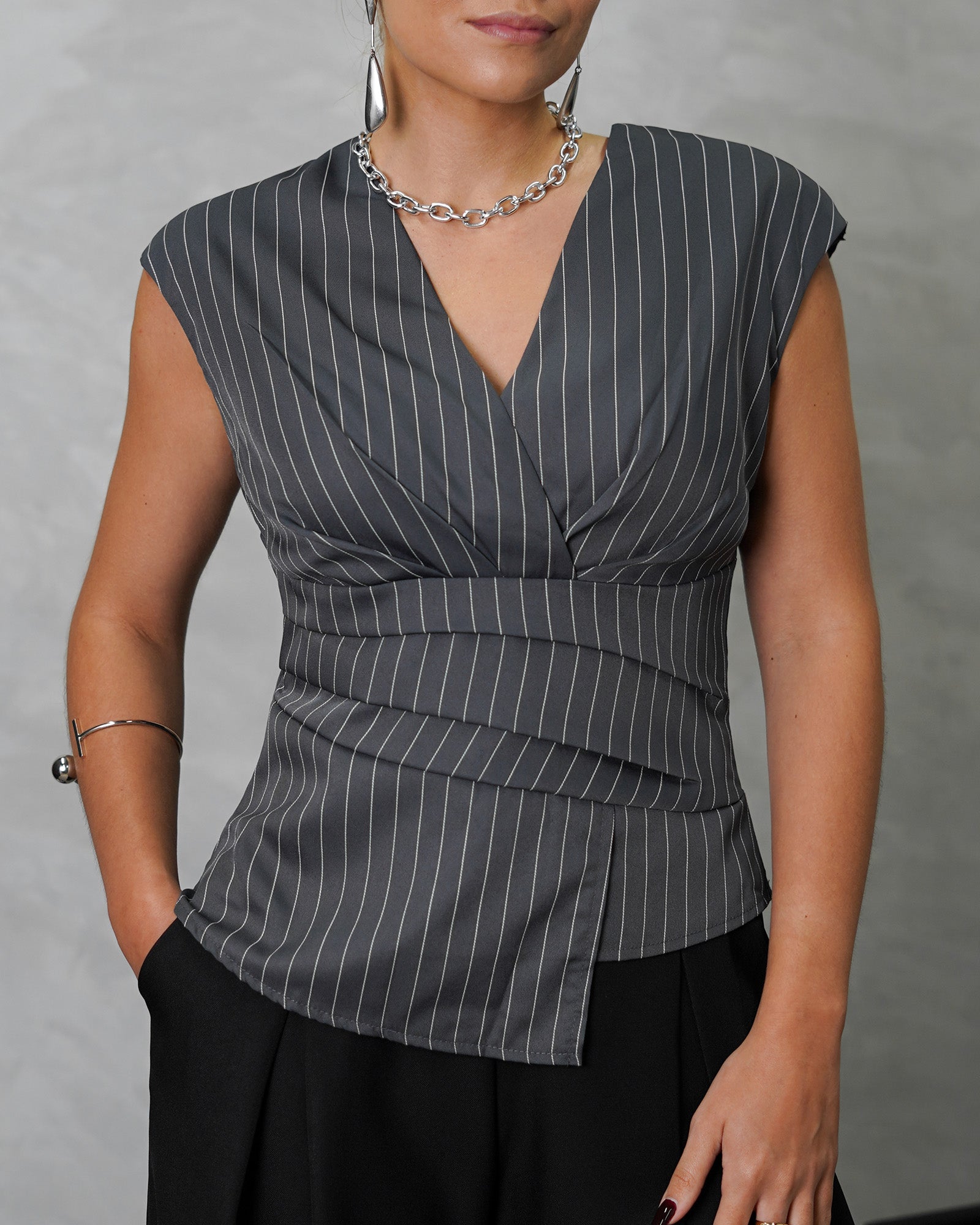 una mujer con blusa sin mangas de rayas verticales gris