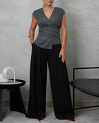 una mujer de cuerpo completo con blusa sin mangas de rayas verticales gris y pantalon negro