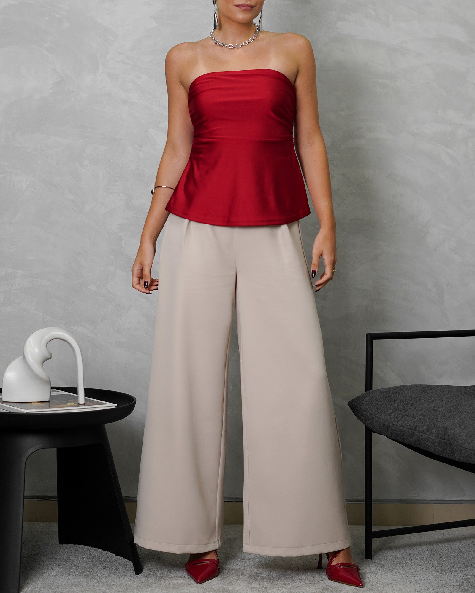 una mujer con Blusa strapless campanada roja satinada y pantalon beige