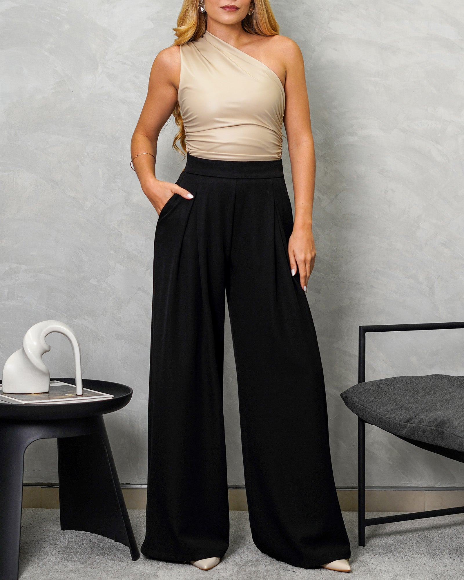 mujer con un body de cuerina asimétrico corte griego beige y pantalon negro