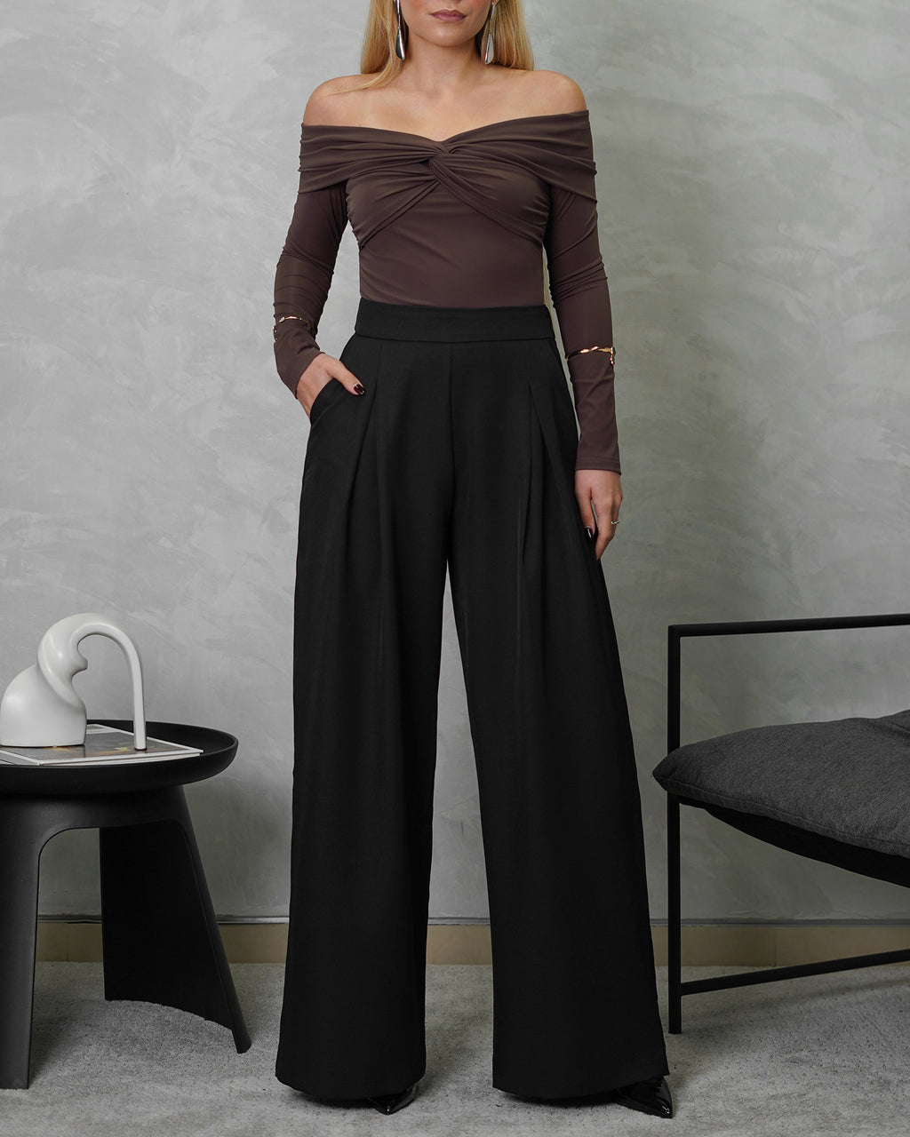 una mujer con un body off shoulder manga larga entrelazado marron y pantalon negro