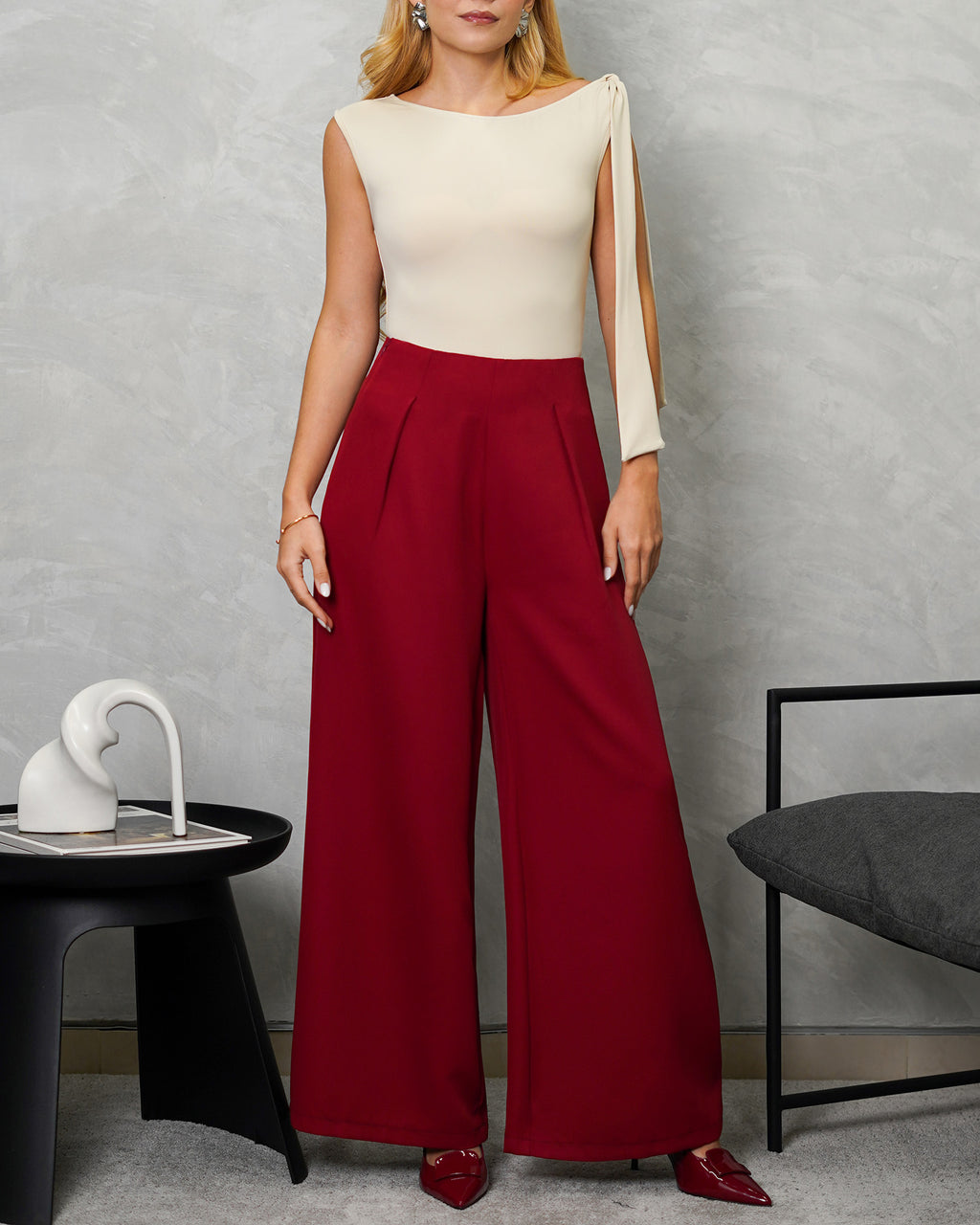 una mujer con body de tira colgante en el hombro marron y pantalon vinotinto