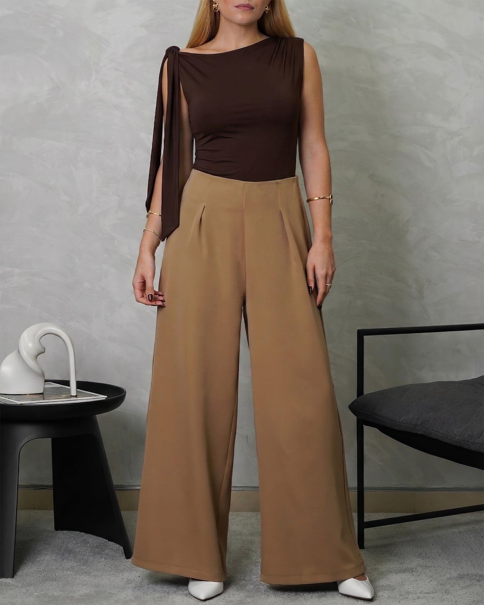 una mujer con body de tira colgante en el hombro marron y pantalon marron claro