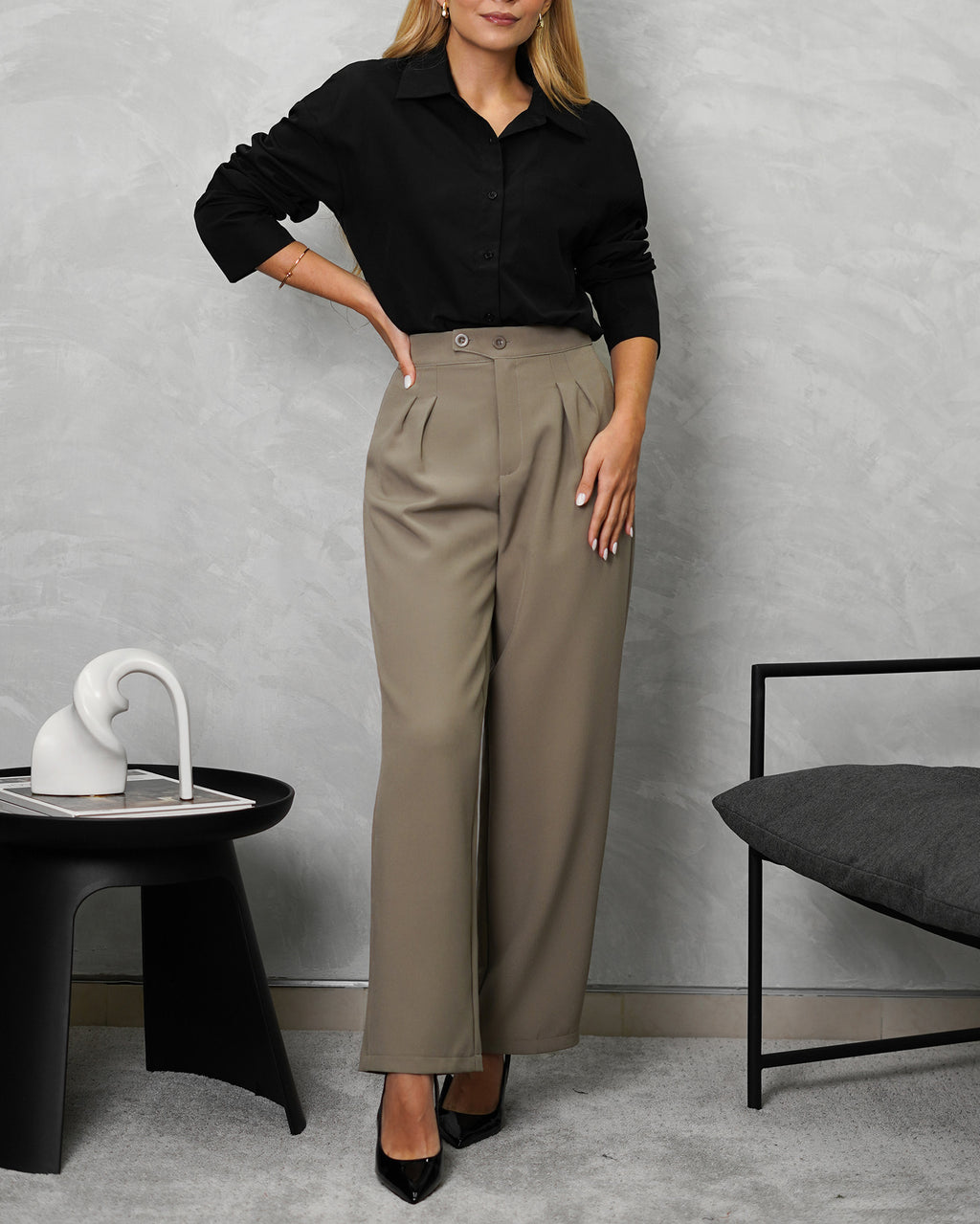 una mujer con camisa de botones manga larga oversized negra y pantalon beige