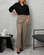 una mujer con camisa de botones manga larga oversized negra y pantalon beige