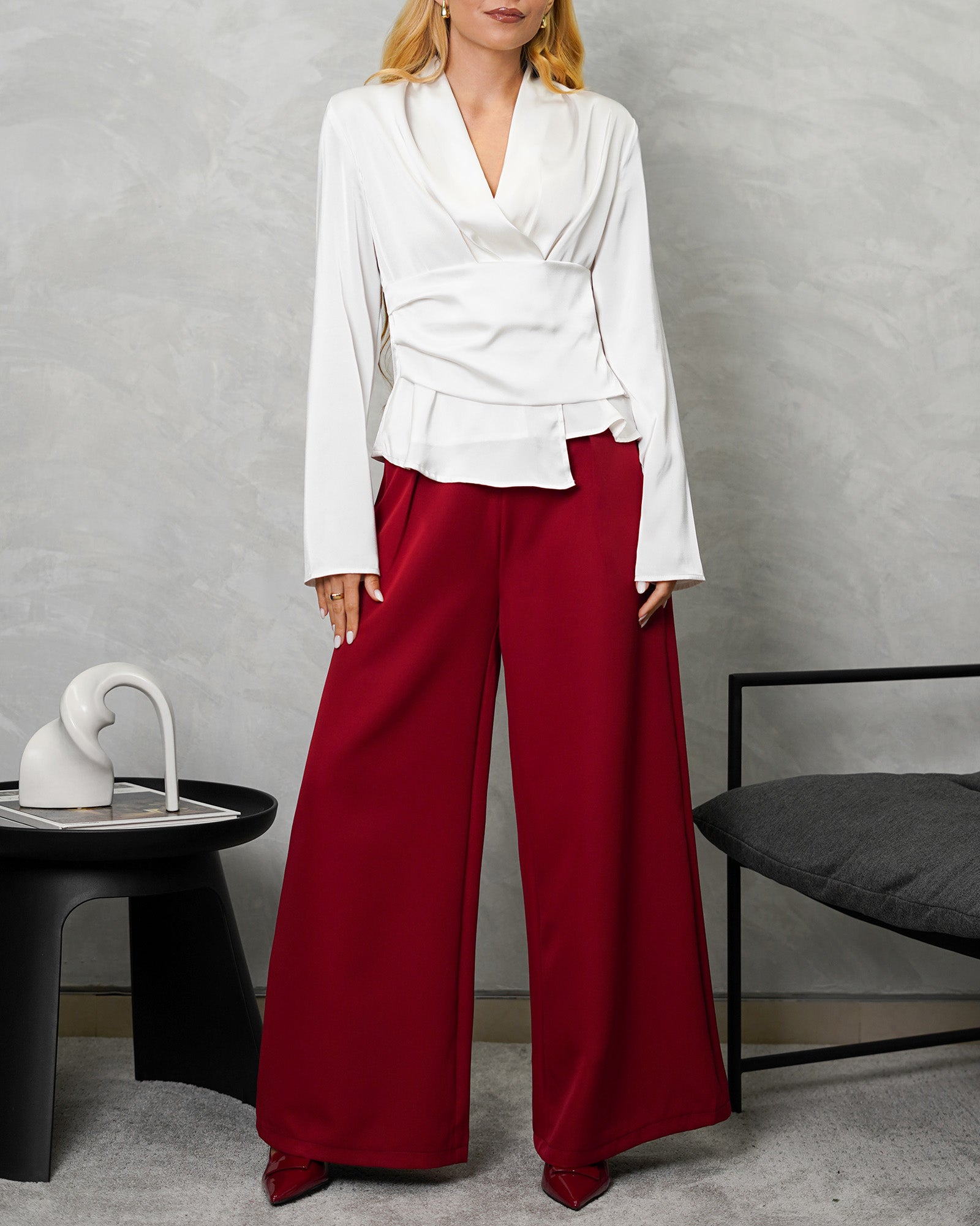 una mujer con camisa manga larga entrelazada blanca y pantalon vino