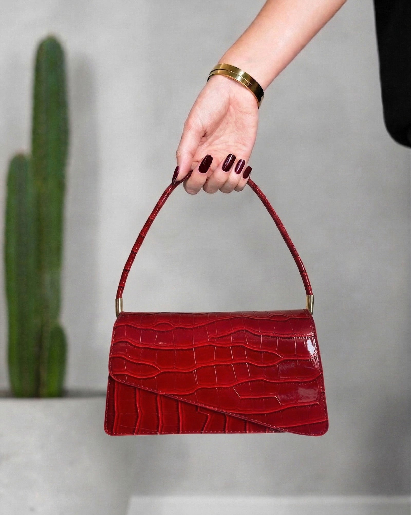 cartera con textura de cocodrilo y solapa asimétrica