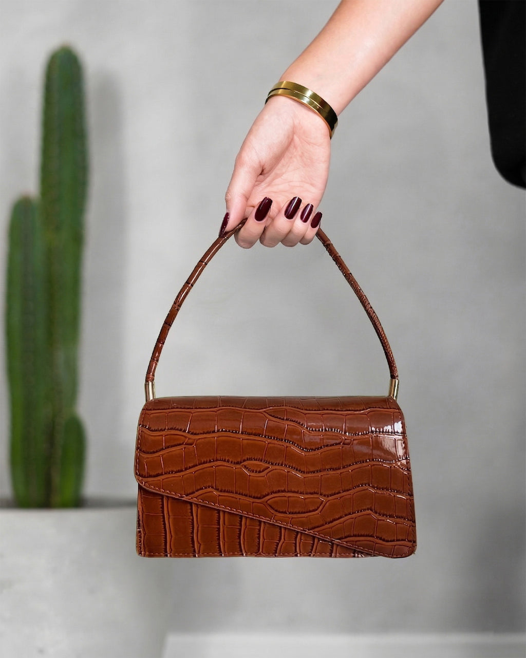 cartera con textura de cocodrilo y solapa asimétrica