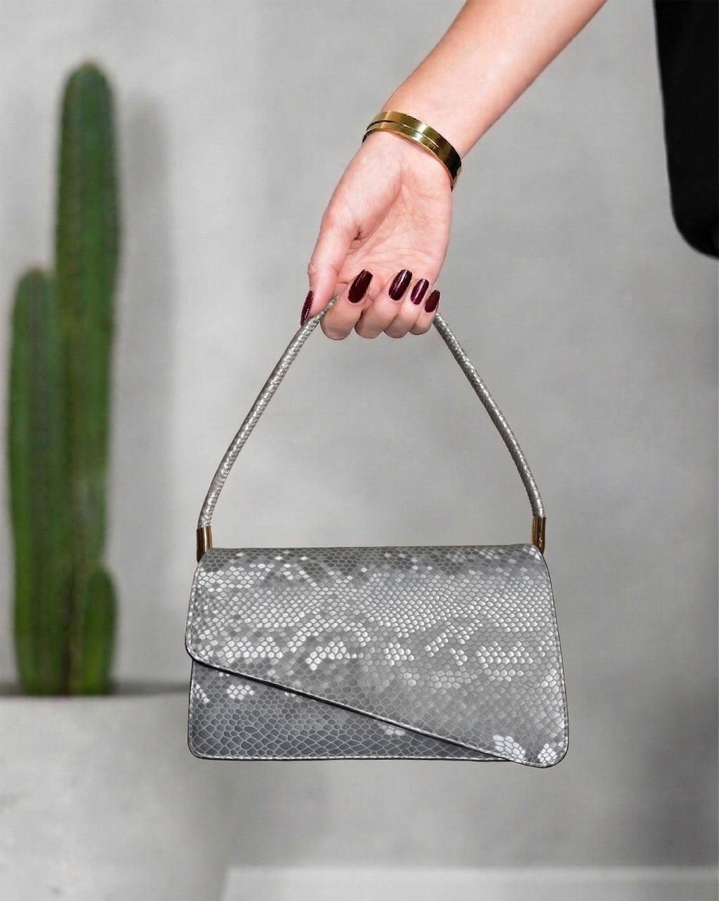 cartera con textura de cocodrilo y solapa asimétrica