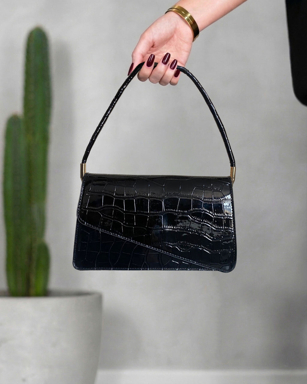 cartera con textura de cocodrilo y solapa asimétrica