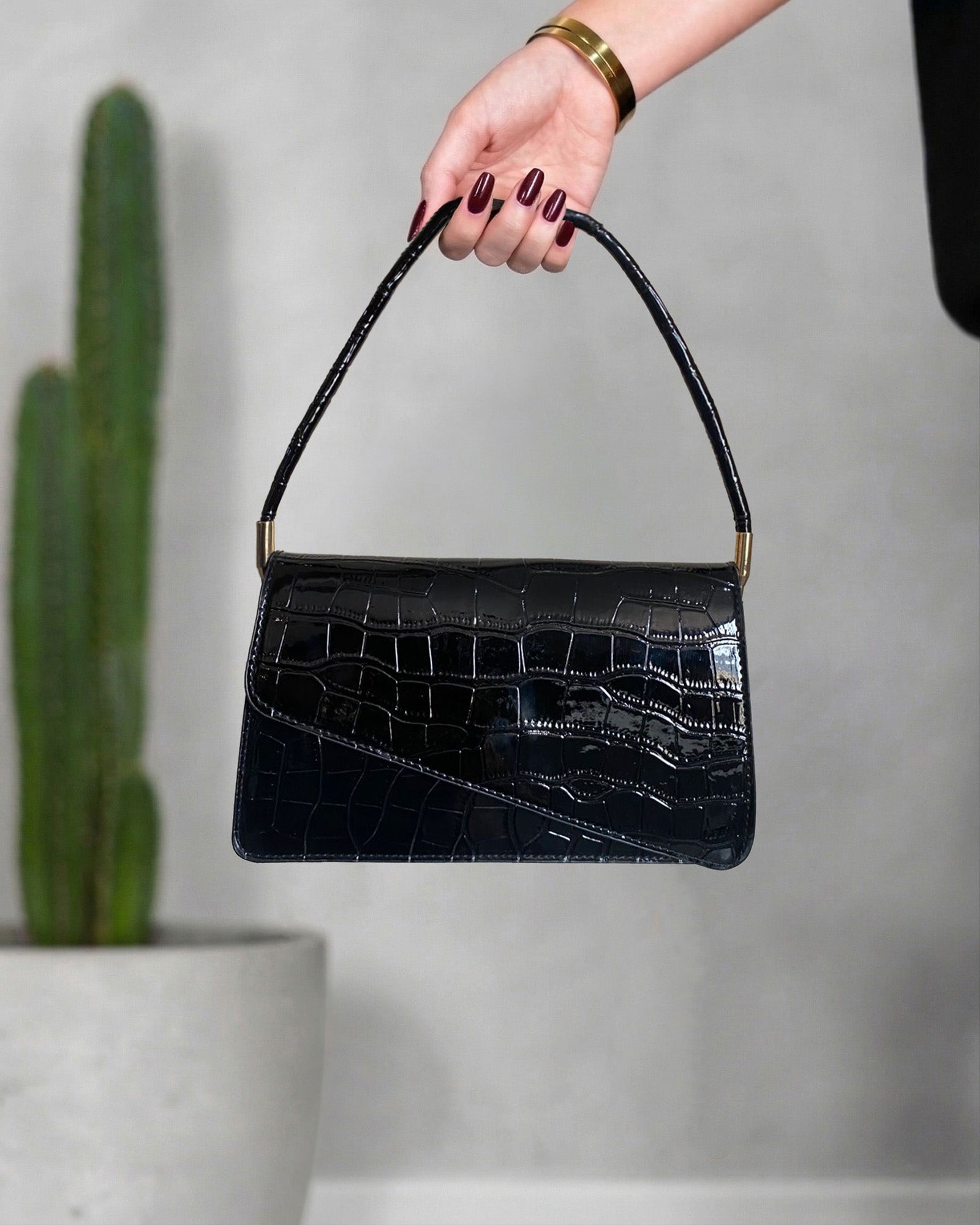 cartera con textura de cocodrilo y solapa asimétrica